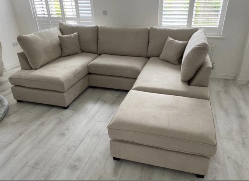 U shaped beige corner sofa with footstool in modern living room.