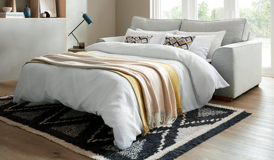 Oslo Fabric Sofa Bed with bedding, showcasing comfort and functionality in a modern living room setting.