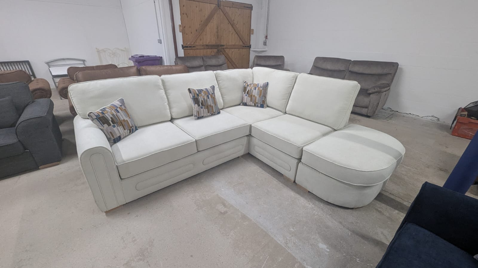 Cream lounger fabric sofa right-hand corner with scatter cushions in warehouse setting.