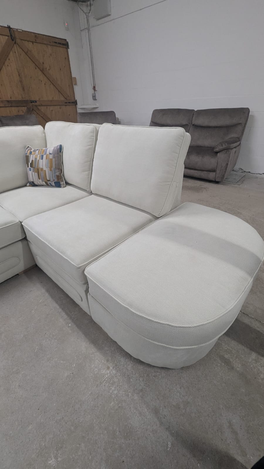 Cream beige lounger fabric sofa with foam-filled seats, right-hand corner design, displayed in a warehouse setting.