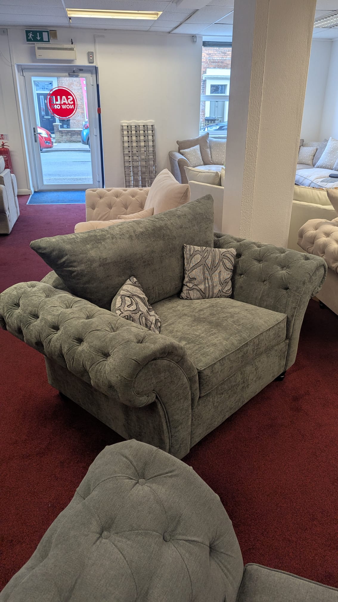 Windsor Chesterfield Cuddle Chair in grey, displayed in a shop setting.