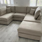 U shaped beige corner sofa with footstool in modern living room.